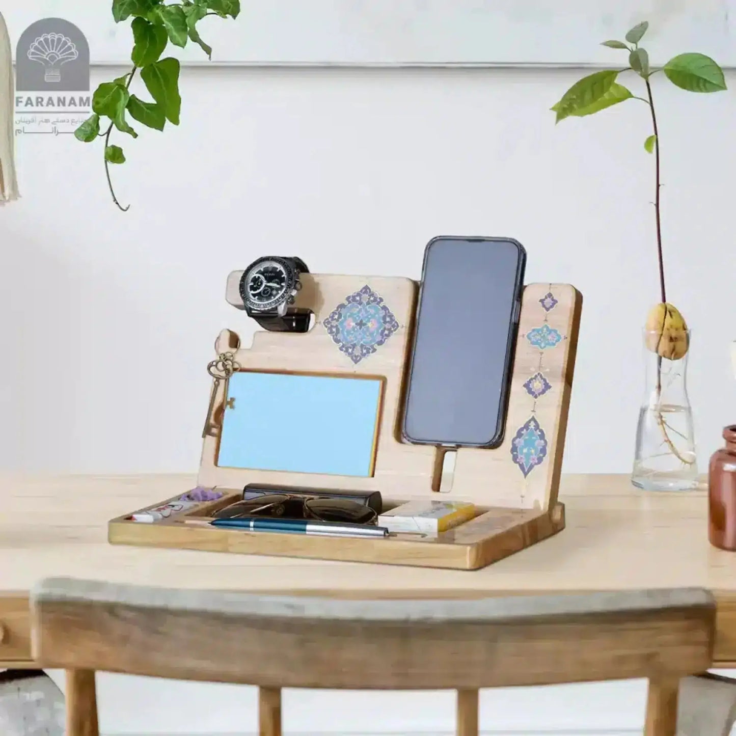 Wooden multi-device stand with tablet, phone, and watch on a desk with plants in the background